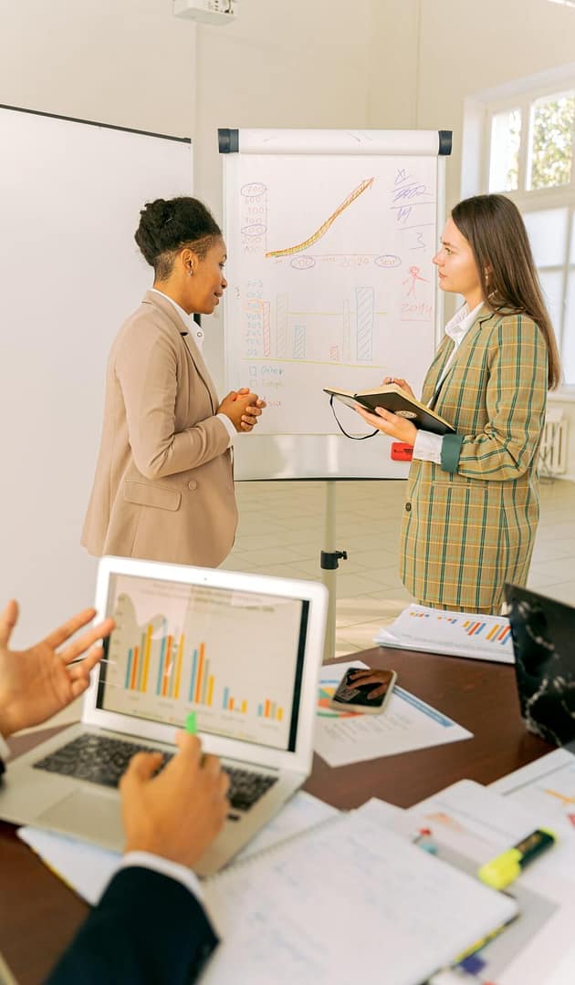 Business meeting discussing charts and metrics at a whiteboard