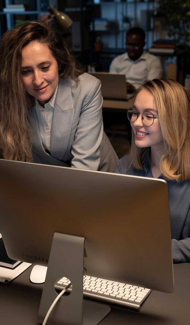 Two colleagues collaborating at a desktop computer in an office