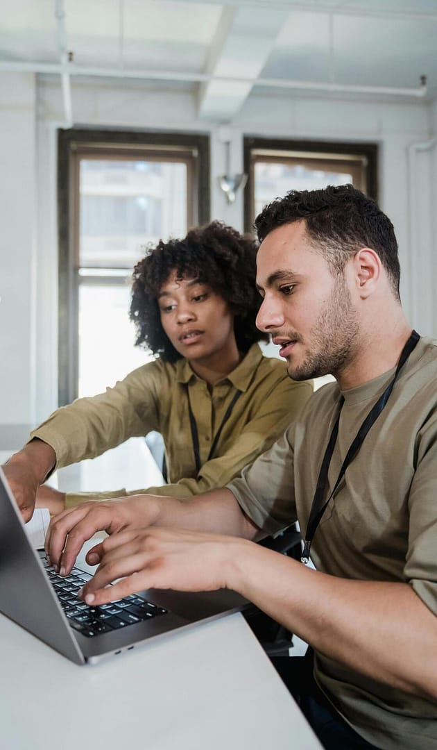 Two colleagues collaborating on a laptop in an office workspace