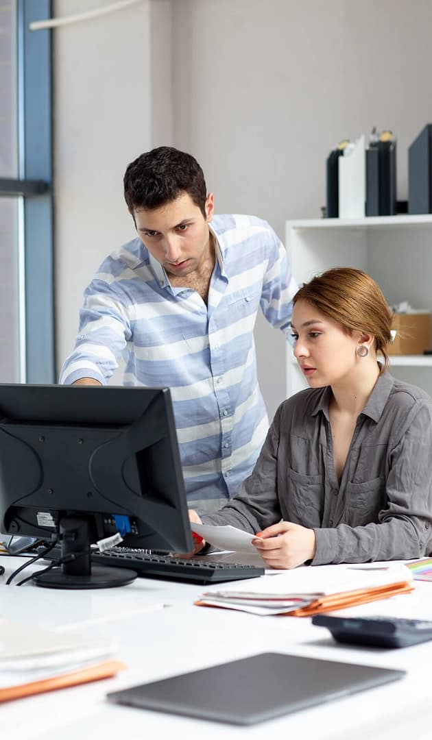 Colleagues reviewing documents and data on a computer in an office
