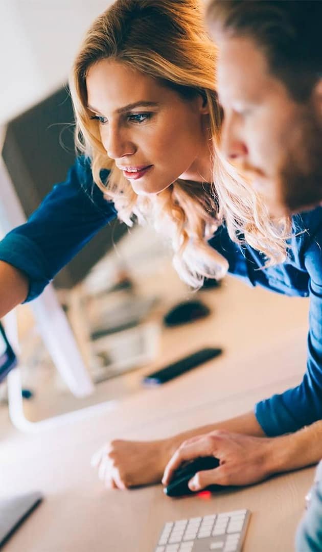 Two specialists reviewing information on a desktop computer during a work session
